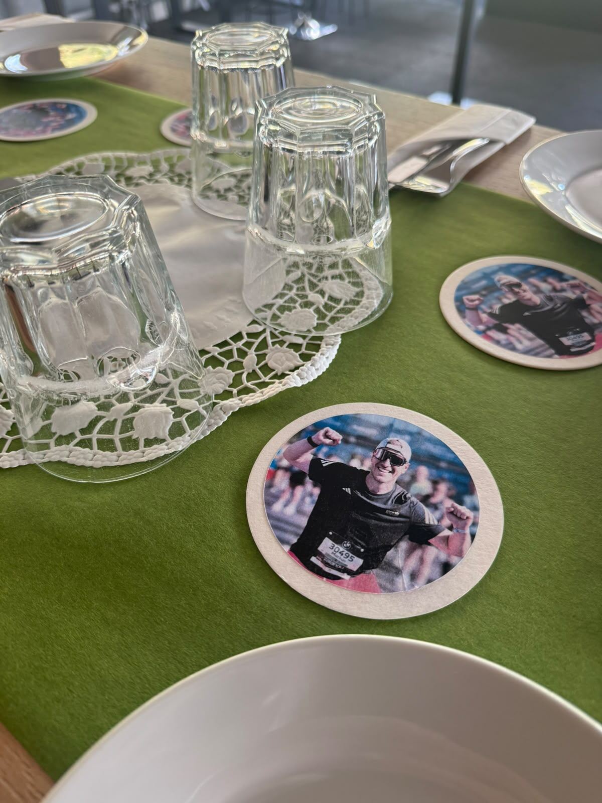 Nahaufnahme: Gläser, Spitzendeckchen und Bierdeckel auf grünem Tischläufer